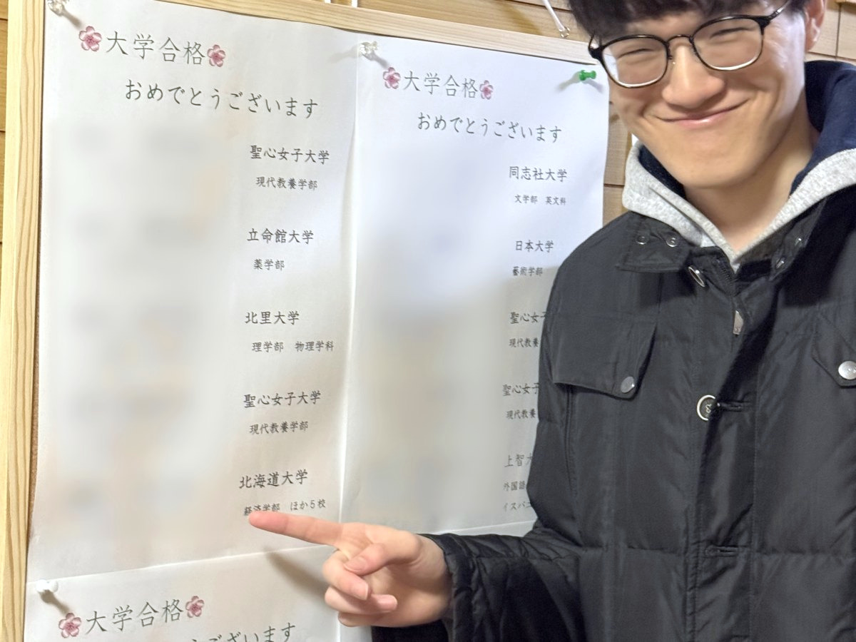 大学合格者の掲示を指さす卒業生